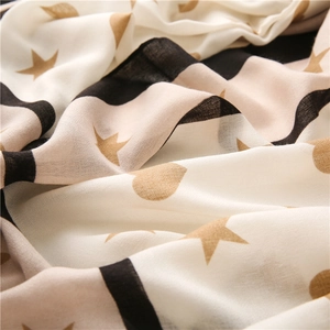 Detailed texture of cotton linen scarf featuring black stripes and gold star heart prints