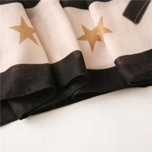 Detail of black and white striped scarf with gold star prints on cotton-linen fabric
