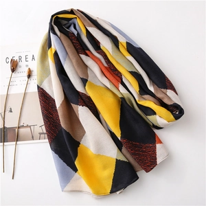 Détail d'une écharpe à motifs géométriques colorés avec des tons jaune et gris sur blanc