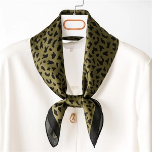Detail of silk leopard print scarf tied on a white shirt collar for elegant styling