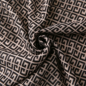 Macro detail of geometric jacquard scarf showing black and beige pattern texture