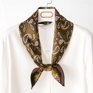 Detail of silk scarf with classic olive green paisley pattern on a white shirt