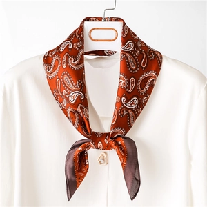 Elegant silk-like paisley square scarf in rust red tied on a white blouse for women