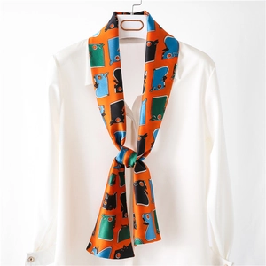 Écharpe étroite orange vif avec imprimés chat ludiques nouée sur un col de chemise blanc