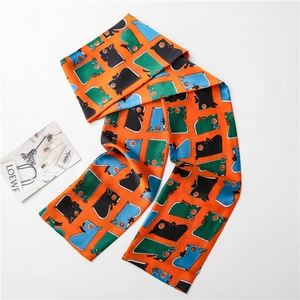 Détail d'un long foulard en soie orange vif avec des motifs géométriques abstraits