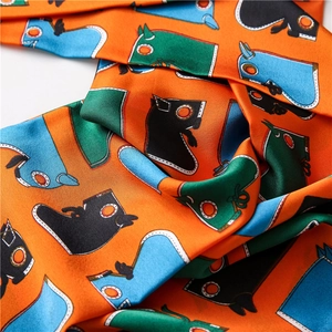 Gros plan détaillé d'un foulard en soie orange avec motifs de chevaux abstraits et sergé