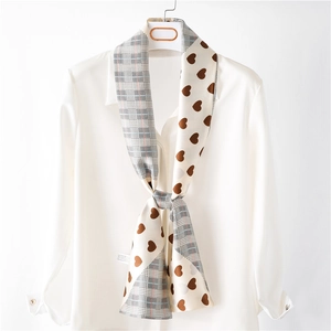 Detail of narrow silk scarf with heart print and grey plaid pattern on white shirt