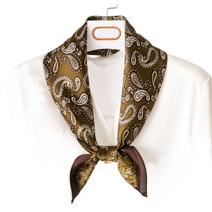 Elegant paisley silk scarf in olive green and brown tied as a bow on a white shirt collar