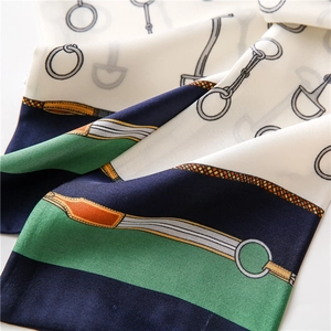 Detail of silk-texture scarf with equestrian print showing smooth fabric and harness motifs