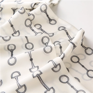 Macro shot of silk texture neckerchief featuring classic dark grey horsebit patterns