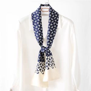 Elegant navy and white chain print satin skinny scarf draped on a white shirt