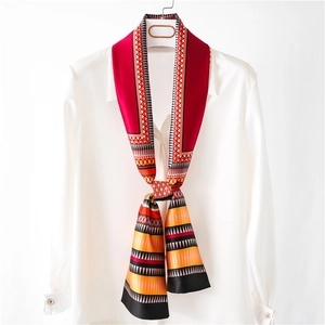 Foulard en soie à motif géométrique rouge élégamment drapé sur une chemise blanche