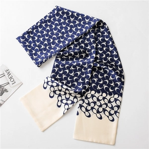 Macro shot of long silk scarf with navy blue interlocking logo patterns on white background