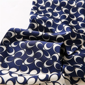 Macro detail of navy and beige interlocking pattern on silk feel fabric scarf