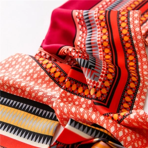 Gros plan d'un foulard en soie bohème aux motifs ethniques rouges et texture soyeuse