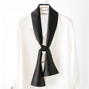 Détail d'un élégant foulard en satin noir noué sur le col d'une chemise blanche chic