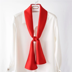 Détail d'un foulard étroit en soie rouge noué sur un chemisier blanc élégant