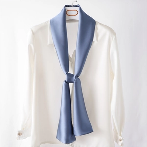 Foulard en satin bleu marine noué sur une chemise blanche pour un look de bureau élégant