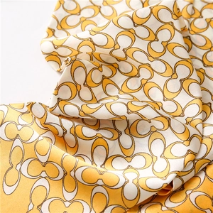 Detail shot of the silky satin scarf showing the yellow and white geometric pattern