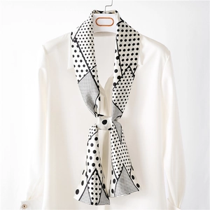 Élégant foulard étroit en soie à pois noir et blanc noué sur un col de chemise blanc