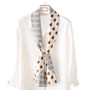 Narrow silk scarf with grey plaid and brown heart print displayed on a white shirt