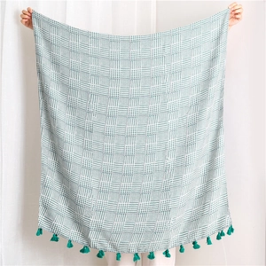 Close-up of a green and white houndstooth shawl with elegant emerald tassel details