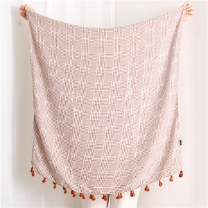Detail of soft brown and white checkered knit shawl with elegant fringe tassels