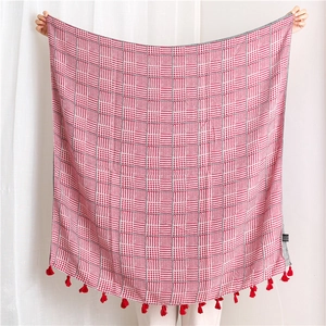 Close-up of red and white houndstooth knit shawl with vibrant red tassel fringe details