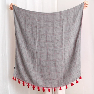 Detail of houndstooth cotton linen shawl with red stripe accents and fringe tassels