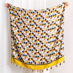 Detail shot of woven plaid cotton scarf featuring colorful geometric patterns and yellow tassels