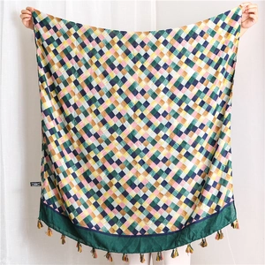 Detail view of woven plaid scarf with multi-color grid patterns and colorful fringe tassels