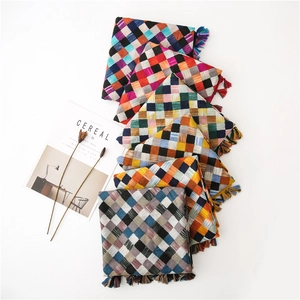 Close-up of woven checkered cotton scarves featuring colorful fringe trim details