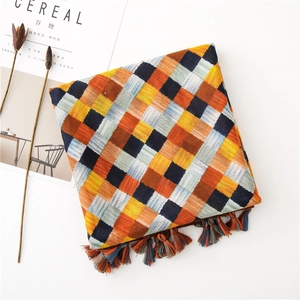Detail of woven plaid scarf with vibrant yellow and navy squares and tassel trim