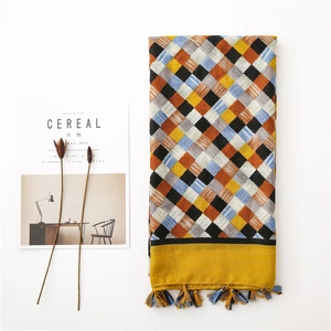 Detailed view of woven plaid scarf with mustard yellow tones and decorative tassels