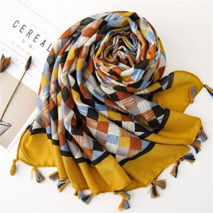 Detail of yellow plaid cotton scarf texture with geometric patterns and fringe tassels