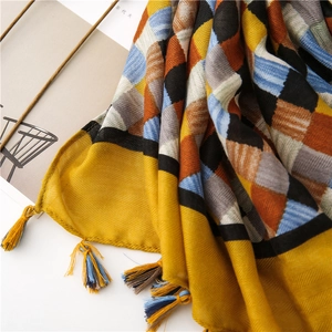 Detail of herringbone weave plaid scarf with yellow and blue tassels on white background
