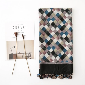 Detail of colorful argyle pattern cotton linen scarf with black fringe tassels on white background