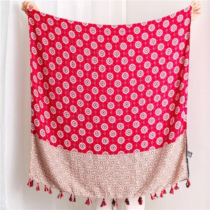 Detail of red and pink scarf with geometric star patterns and tassel edge on white background