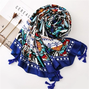 Ethnic print scarf with geometric patterns and tassels, displayed with artistic props