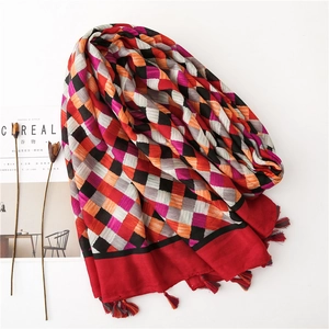 Detail of colorful geometric diamond pattern cotton linen scarf with red fringe tassels