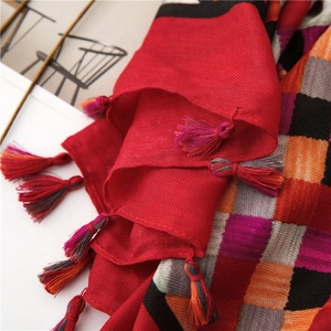 Detail of red herringbone weave scarf with colorful geometric patterns and fringe