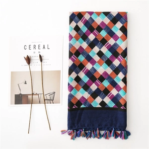Detail view of cotton linen scarf with harlequin check patterns and colorful tassel charms
