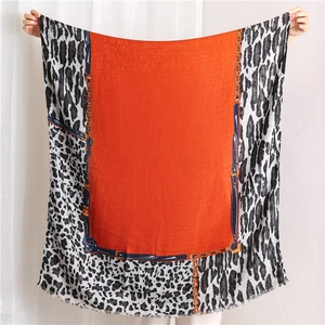 Détail d'une écharpe léopard avec centre orange, motifs chaînes et bords effilochés