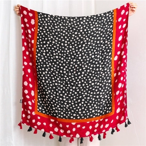 Détail d'une écharpe léopard avec pois audacieux, bords rouges et pompons à franges