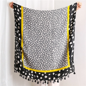 Détail de l'écharpe à motif léopard avec bordure jaune et glands à franges gris