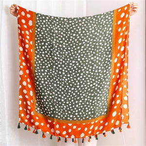 Détail d'écharpe léopard avec coutures contrastées orange et vert foncé et pompons