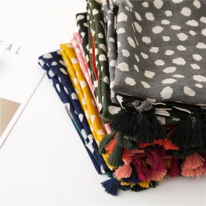 Gros plan d'écharpes à pois colorées avec pompons empilées dans diverses nuances