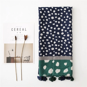 Mise à plat d'une écharpe à pois bleu marine et vert avec pompons et magazine de style