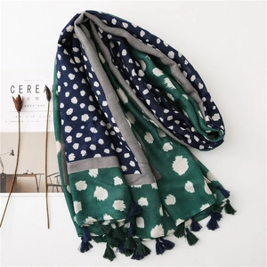 Détail d'une écharpe longue avec imprimé léopard, pompons et texture douce en coton et lin