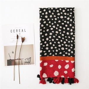 Détail d'une écharpe à pois bicolore avec des franges rouges et un design élégant